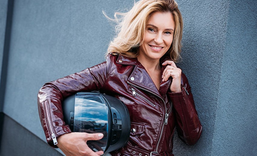 Teilkaskoversicherung Motorrad - Frau in Lederjacke hält Helm im Arm